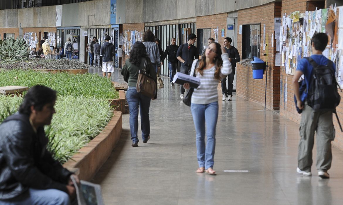 Estudantes caminhando em um corredor que parece um ambiente de universidade